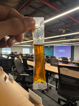 An 8g NEKT Ashwagandha Saffron Honey sachet, held up to show the printed foil pack